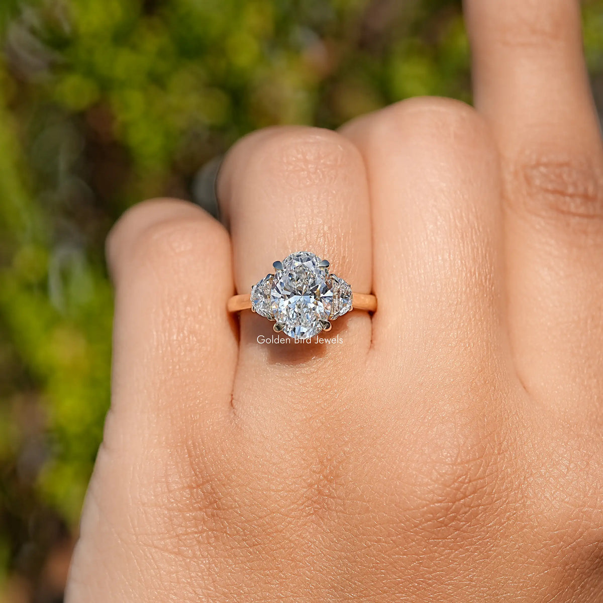 Three-stone diamond engagement ring with center stone and side stones, close-up on hand