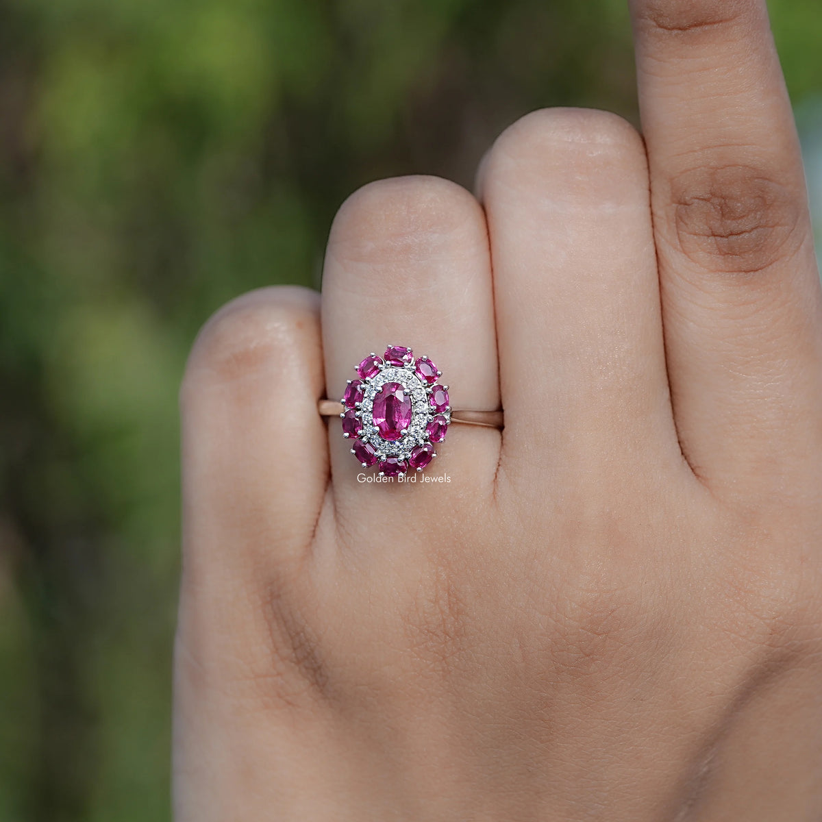 Oval pink gemstone double halo engagement ring on an open palm