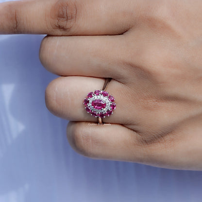 Pink gemstone double halo engagement ring on a closed hand