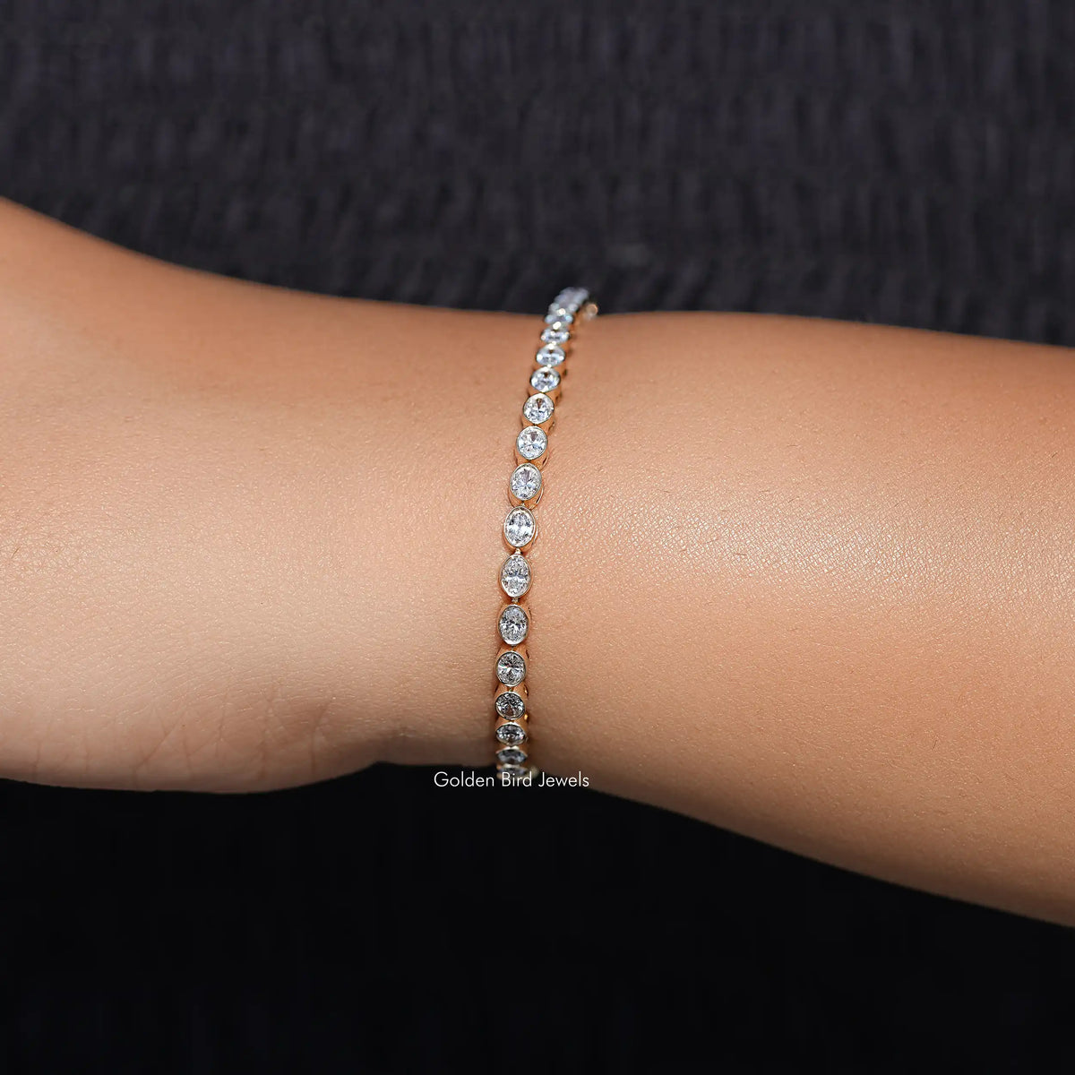 Silver-tone oval-cut diamond tennis bracelet on wrist with sparkling oval stone row