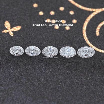 Five oval-cut loose lab diamonds arranged in a row on dark fabric
