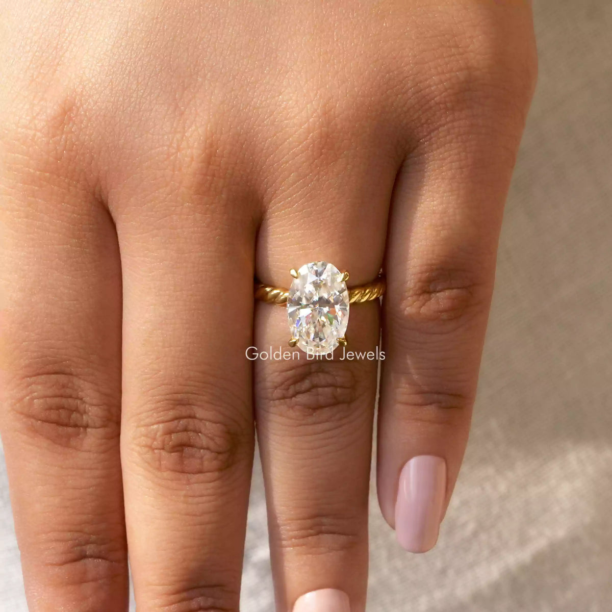 Oval-cut moissanite solitaire ring with gold-tone band and oval stone in 4-prong setting