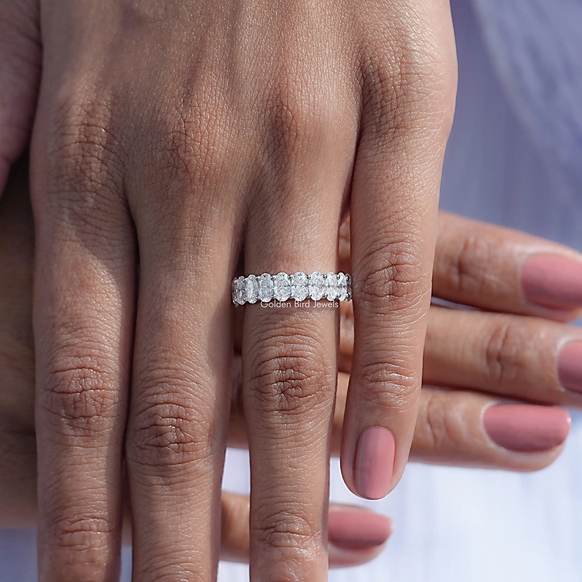 14K white gold half eternity band with oval moissanite stones, straight-on on finger