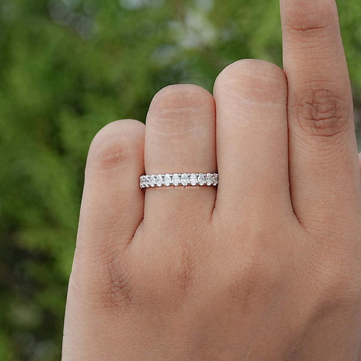Sterling silver half-eternity ring with sparkling oval moissanite stone row on finger
