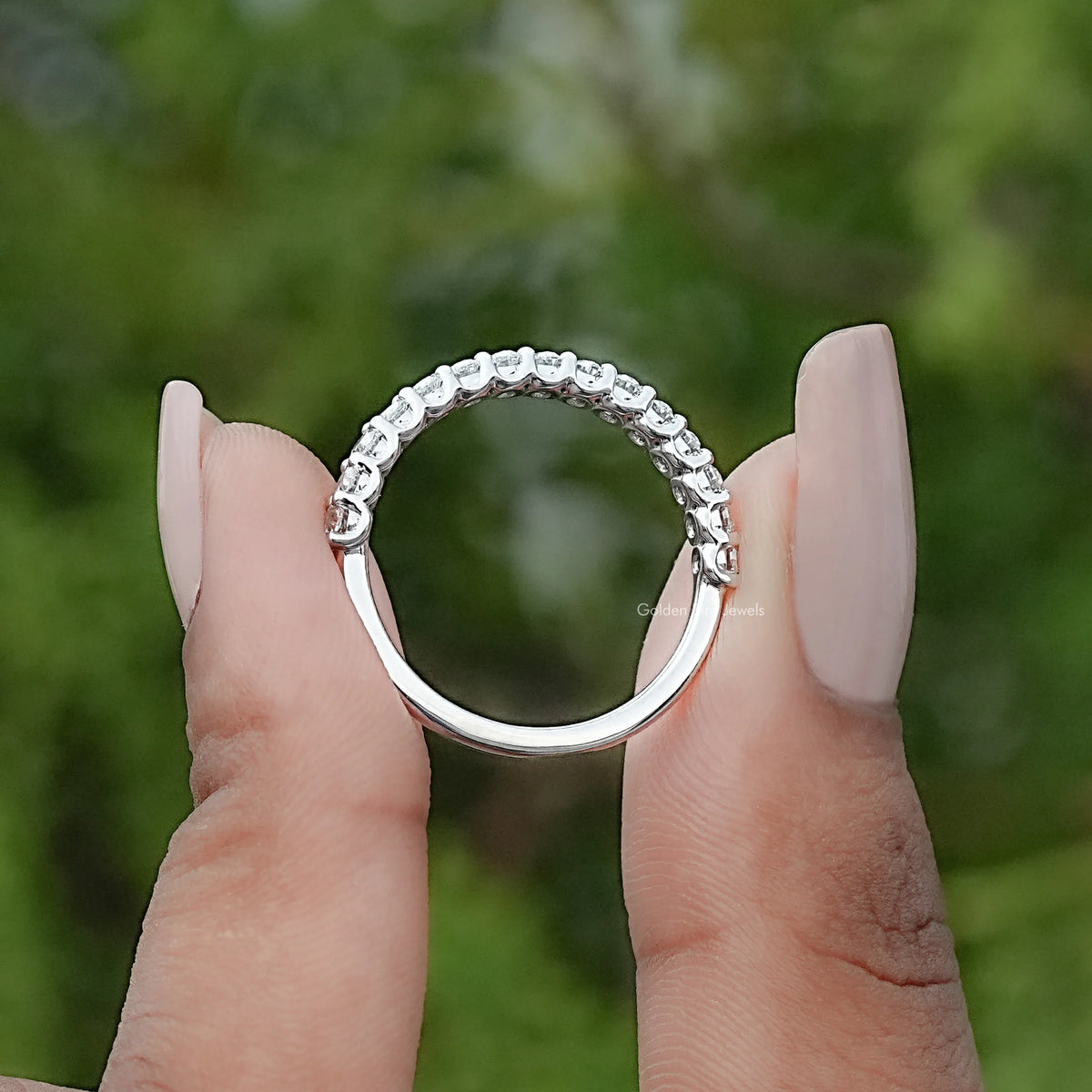 Oval moissanite half-eternity ring with bezel-set stones in a curved band, side view