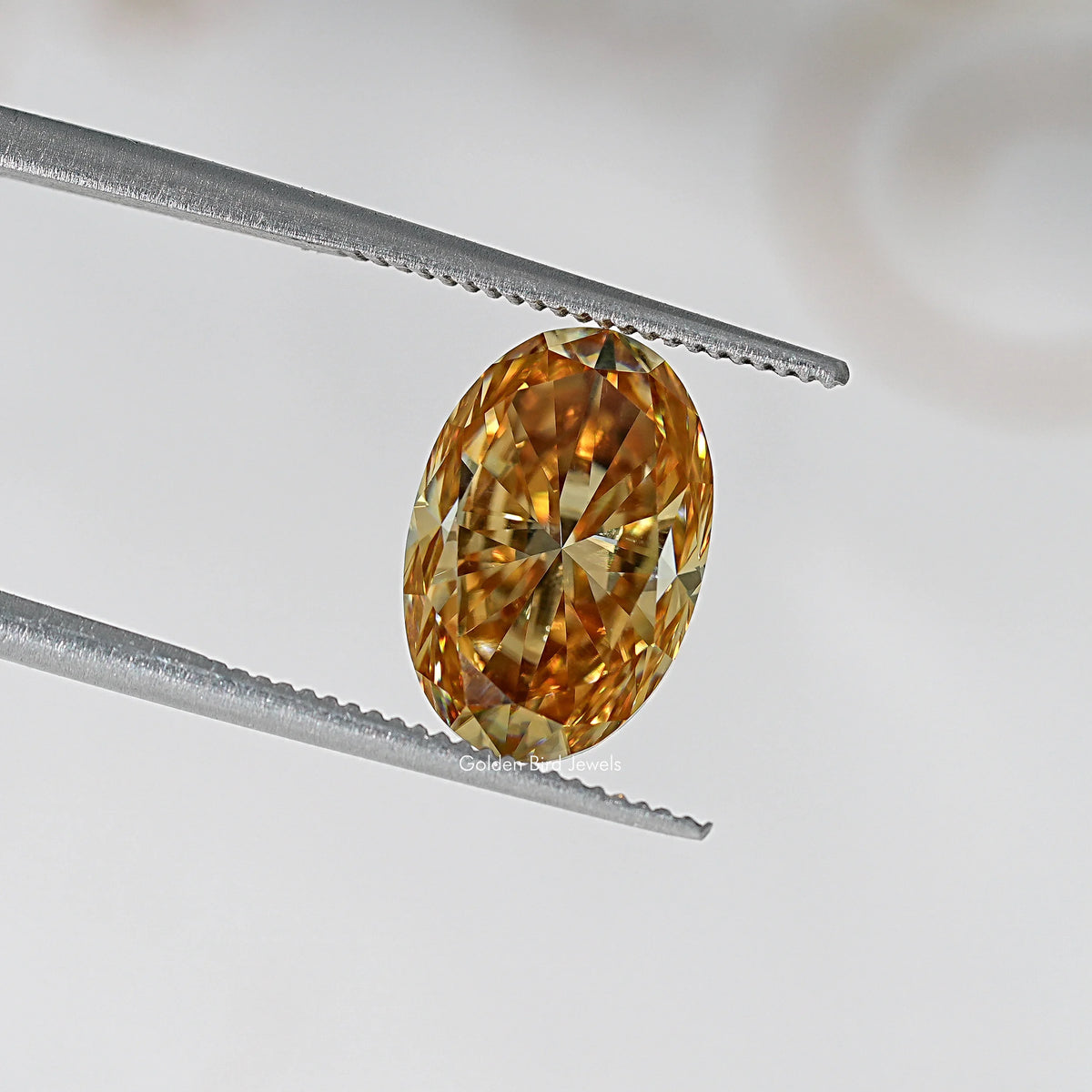 Oval champagne moissanite loose stone in tweezers, warm honey-gold sparkle