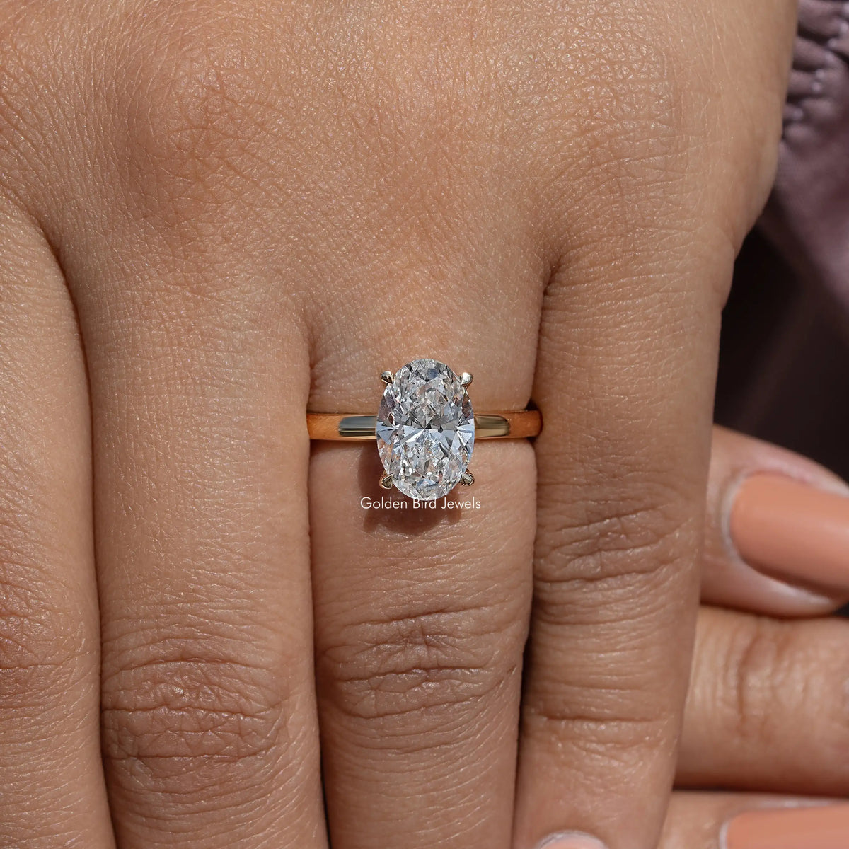 Oval lab diamond solitaire ring on hand, gold band with low-profile four-prong mount