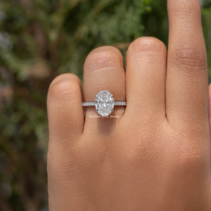 Oval-cut moissanite engagement ring on hand, prong-set center stone and pave band
