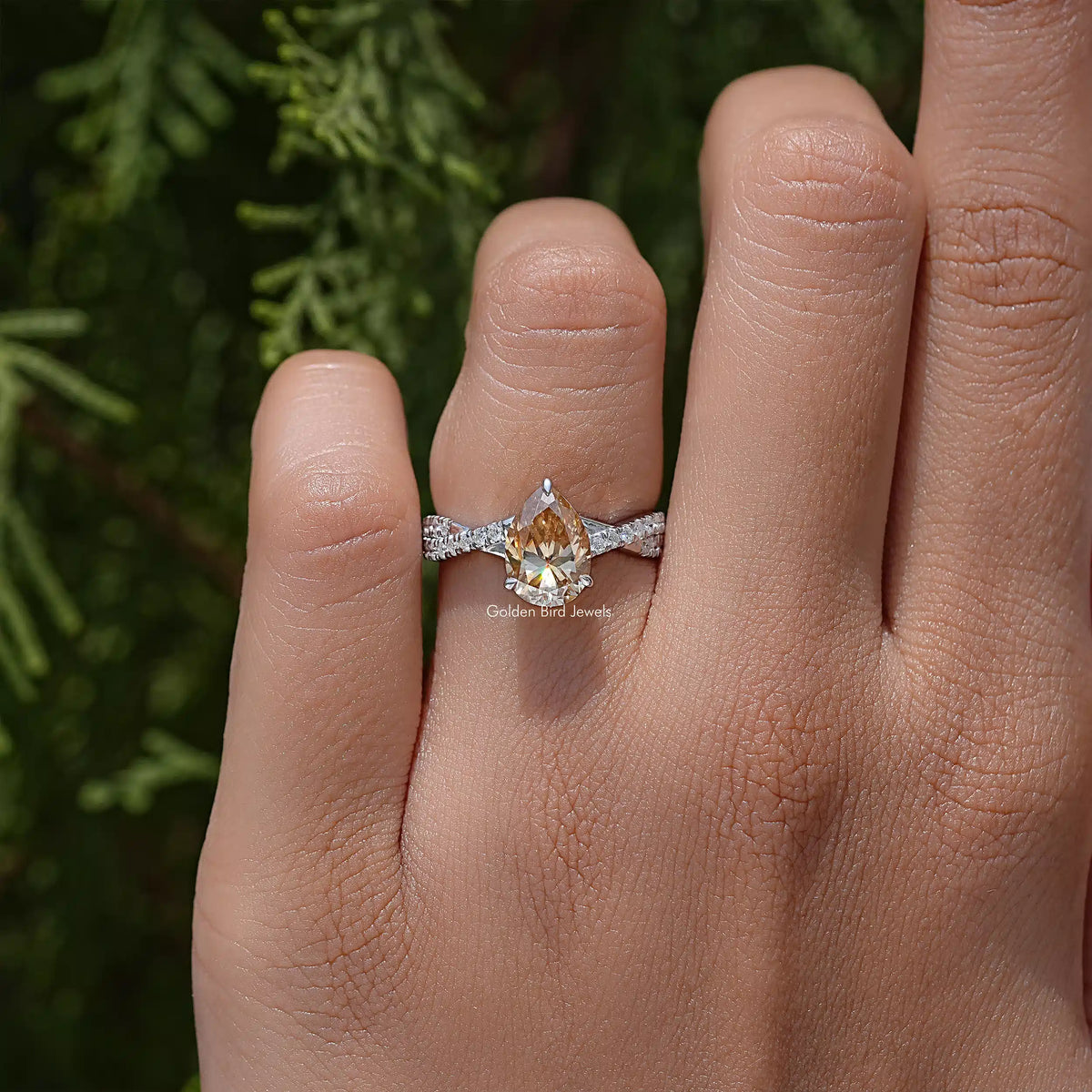Pear moissanite ring with twisted shank and accent stones on a hand