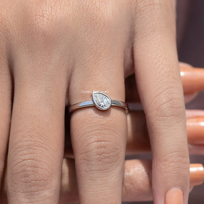 Silver solitaire ring with bezel-set pear-shaped diamond, slim band view from front