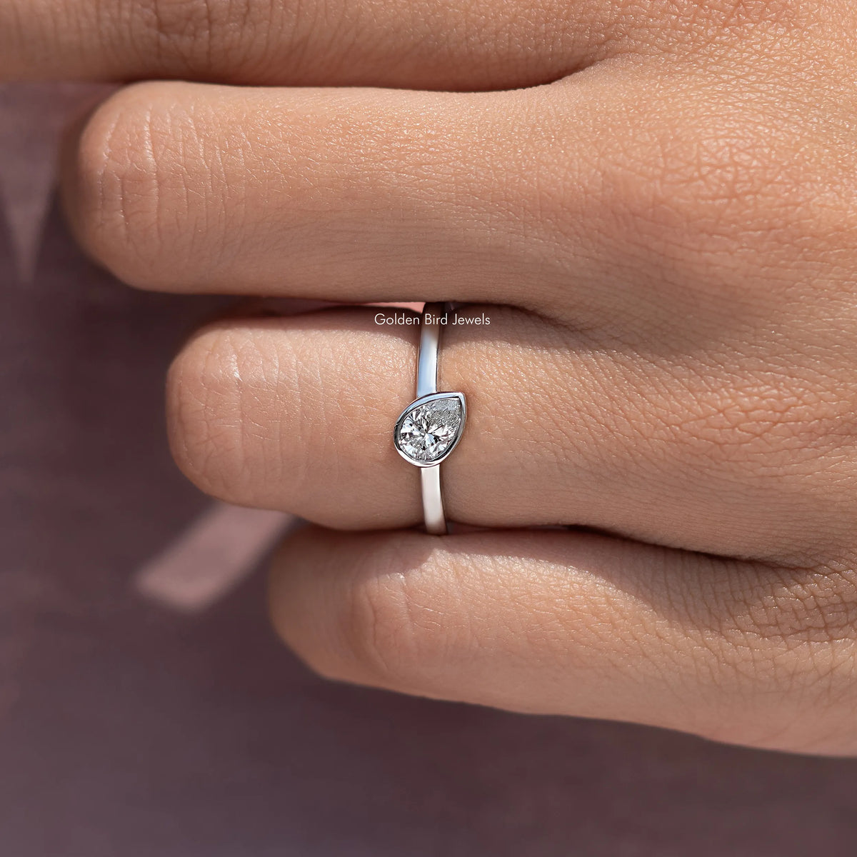 Silver solitaire ring with bezel-set pear-shaped diamond, side profile on finger