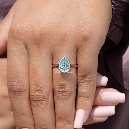 Sterling silver bezel-set solitaire ring with pear-cut light blue stone on hand