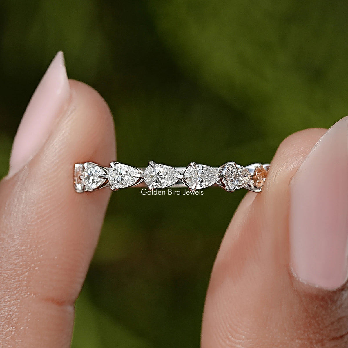Pear-cut diamond eternity band with prong-set stones on a slim silver ring