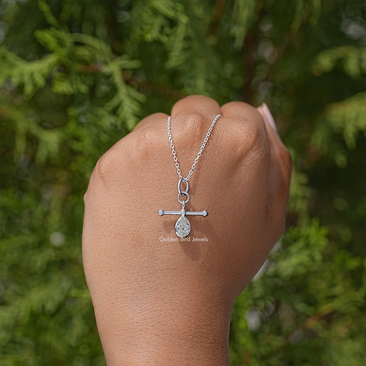 Silver pear-cut bezel pendant necklace on arm with teardrop stone in bezel setting