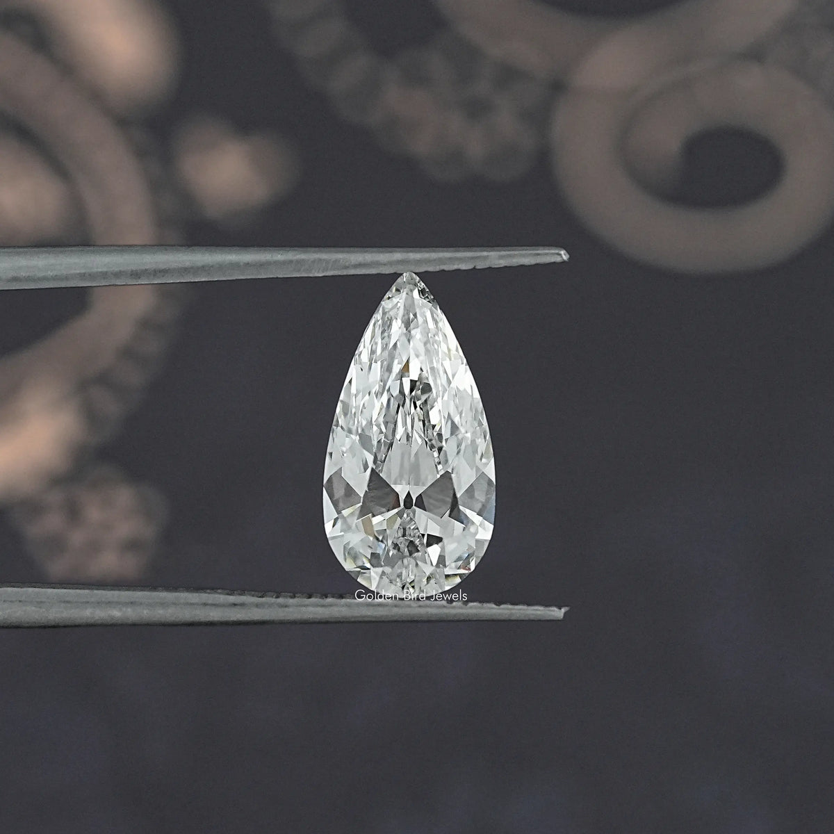 Pear-cut lab-grown diamond held in tweezers, clear white teardrop facets
