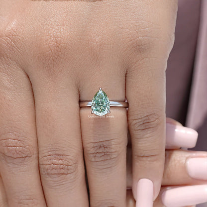 Close-up of sterling silver pear-cut moissanite engagement ring band, green center stone