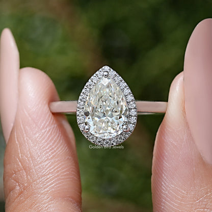 Pear-cut moissanite center stone with halo and pave border, silver engagement ring