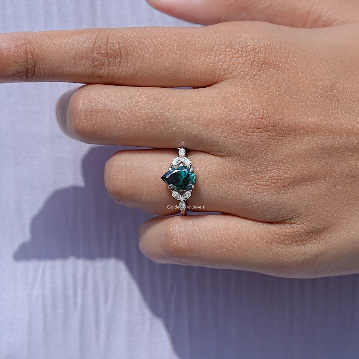 Green moissanite engagement ring with pear-cut center and sparkling round halo