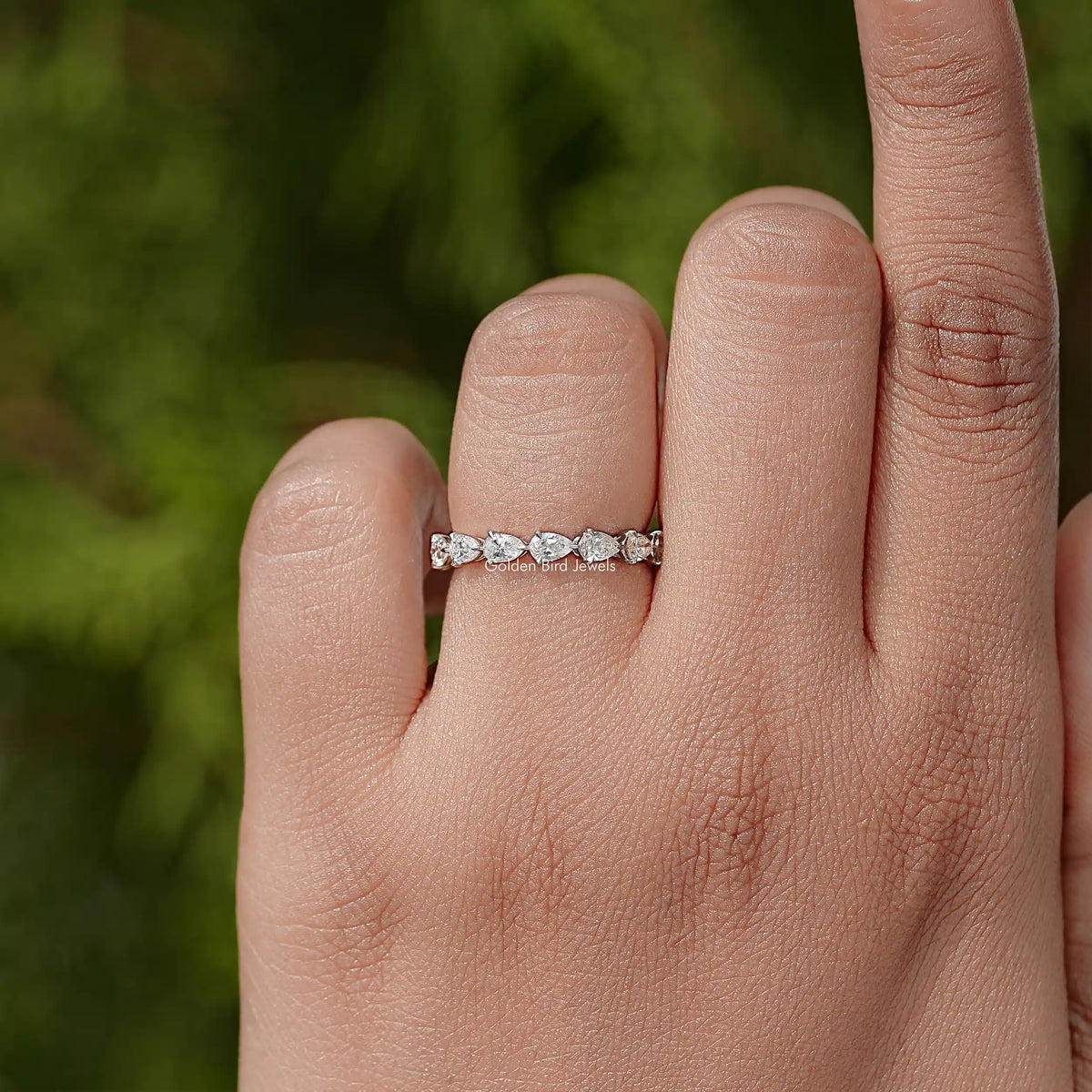 Pear-cut diamond eternity band on finger, slim silver band with stones all around