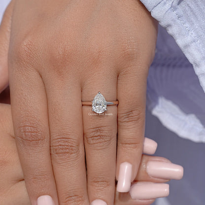 Pear-cut solitaire engagement ring on finger, clear pear-shaped stone in silver setting