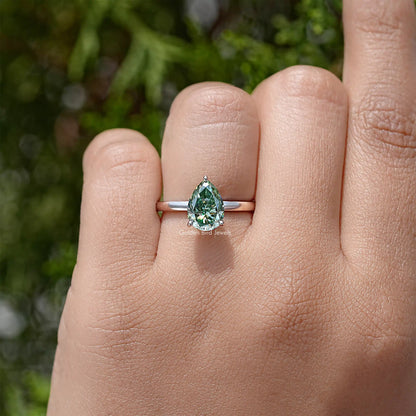 Sterling silver pear-cut moissanite engagement ring on hand, green center stone