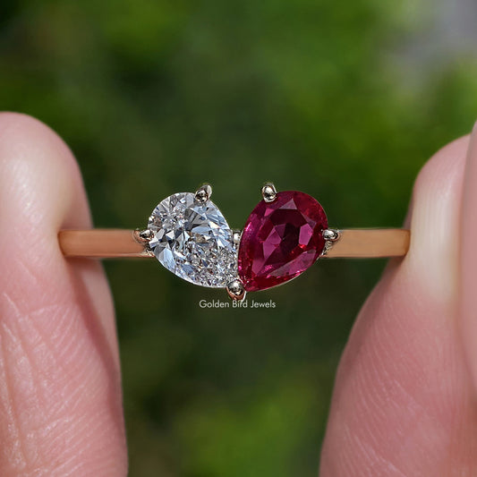 Gold-tone engagement ring with large round diamond and red pear-cut gemstone centerpiece