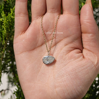 Gold-tone pear-shaped bezel solitaire pendant on fine chain, resting on open palm