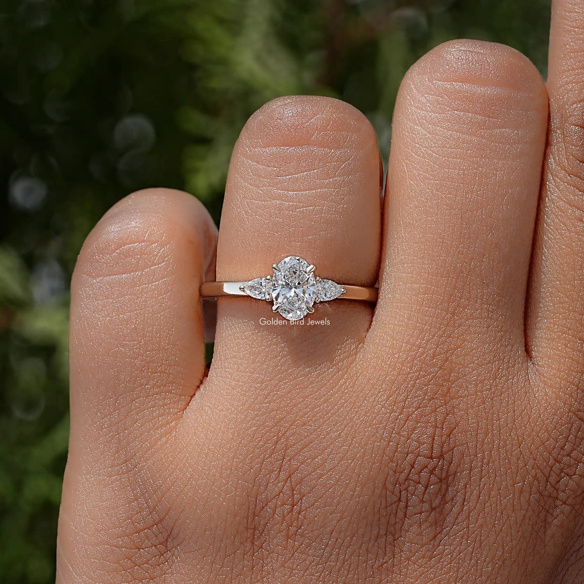 Three-stone lab-grown diamond ring on hand, small round side stones around center