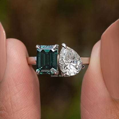 Two-stone ring detail: emerald-cut green stone with large pear-cut clear stone