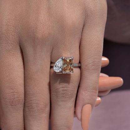 Toi et moi ring detail on hand, pear clear stone and square warm brown center moissanite