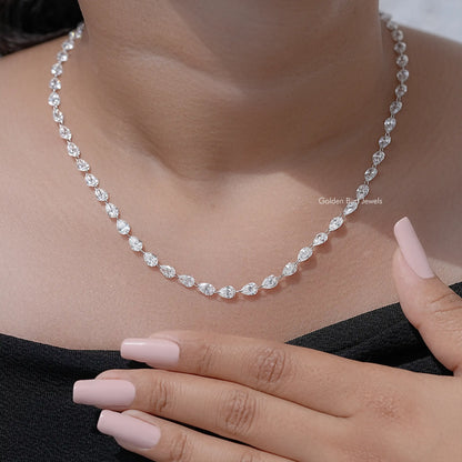 Silver pear-cut diamond tennis necklace with oval links, hand close-up