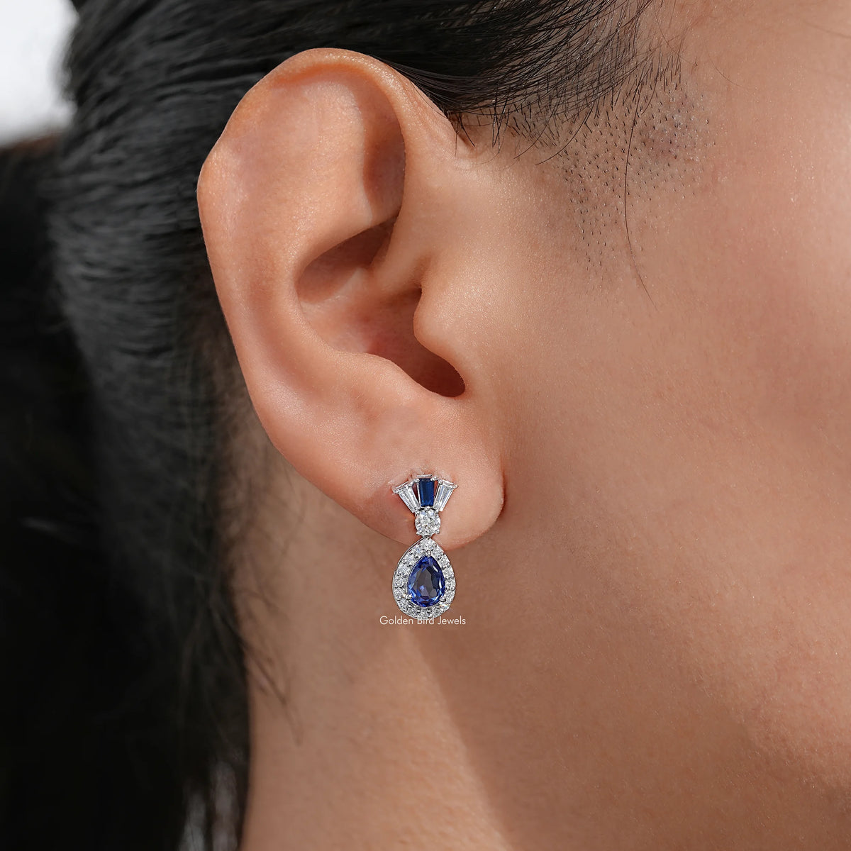 Blue pear-cut halo dangle earrings with small diamond accents, silver-tone drop