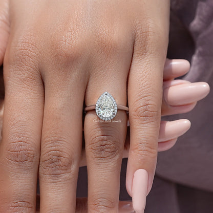 Pear-cut moissanite halo engagement ring on hand, pear center with side accents