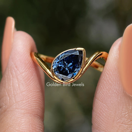 Curved solitaire ring with large blue pear-cut gemstone and gold band