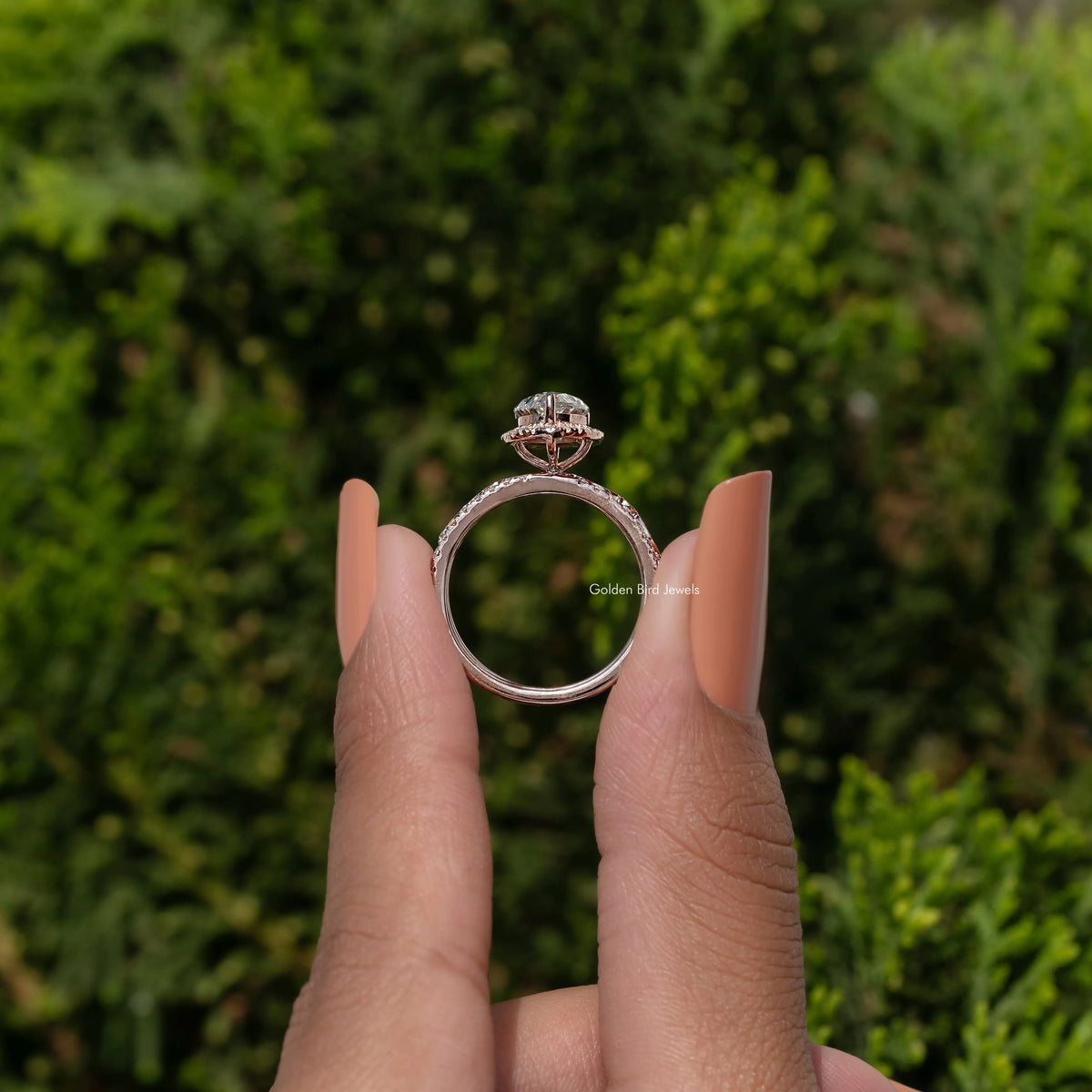Pear-cut moissanite halo bridal ring set, side view held between fingers