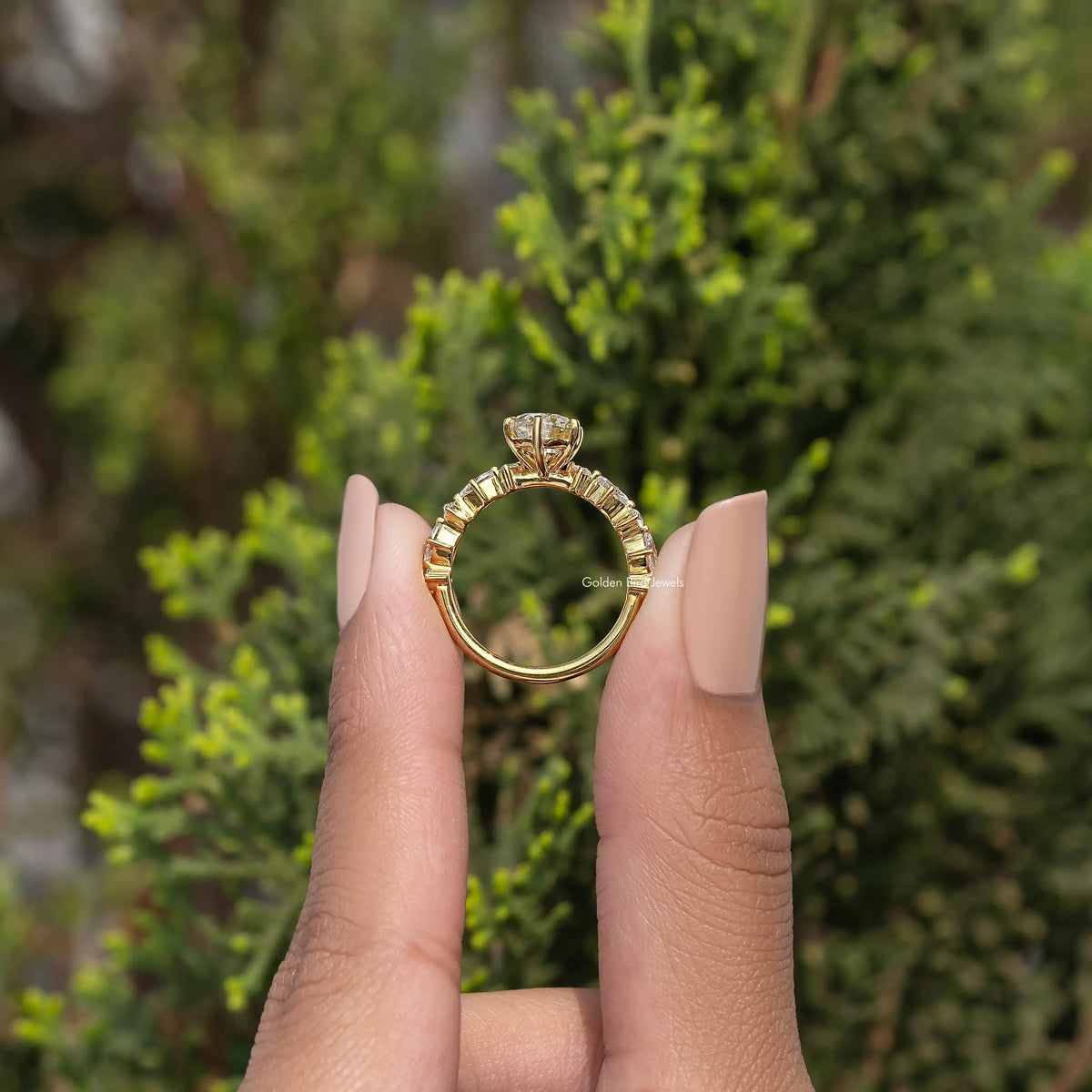 Gold-tone pear-cut moissanite engagement ring with halo-like setting and detailed band
