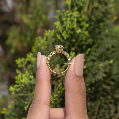 Gold-tone pear-cut moissanite engagement ring with halo-like setting and detailed band