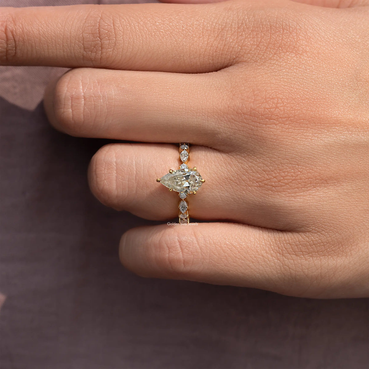 Moissanite engagement ring showing pear-cut center stone and small side accents on prongs
