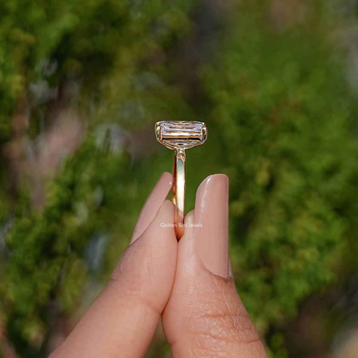 Gold-tone ring top view with rectangular emerald-cut moissanite in pronged setting