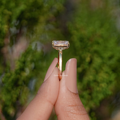 Gold-tone ring top view with rectangular emerald-cut moissanite in pronged setting
