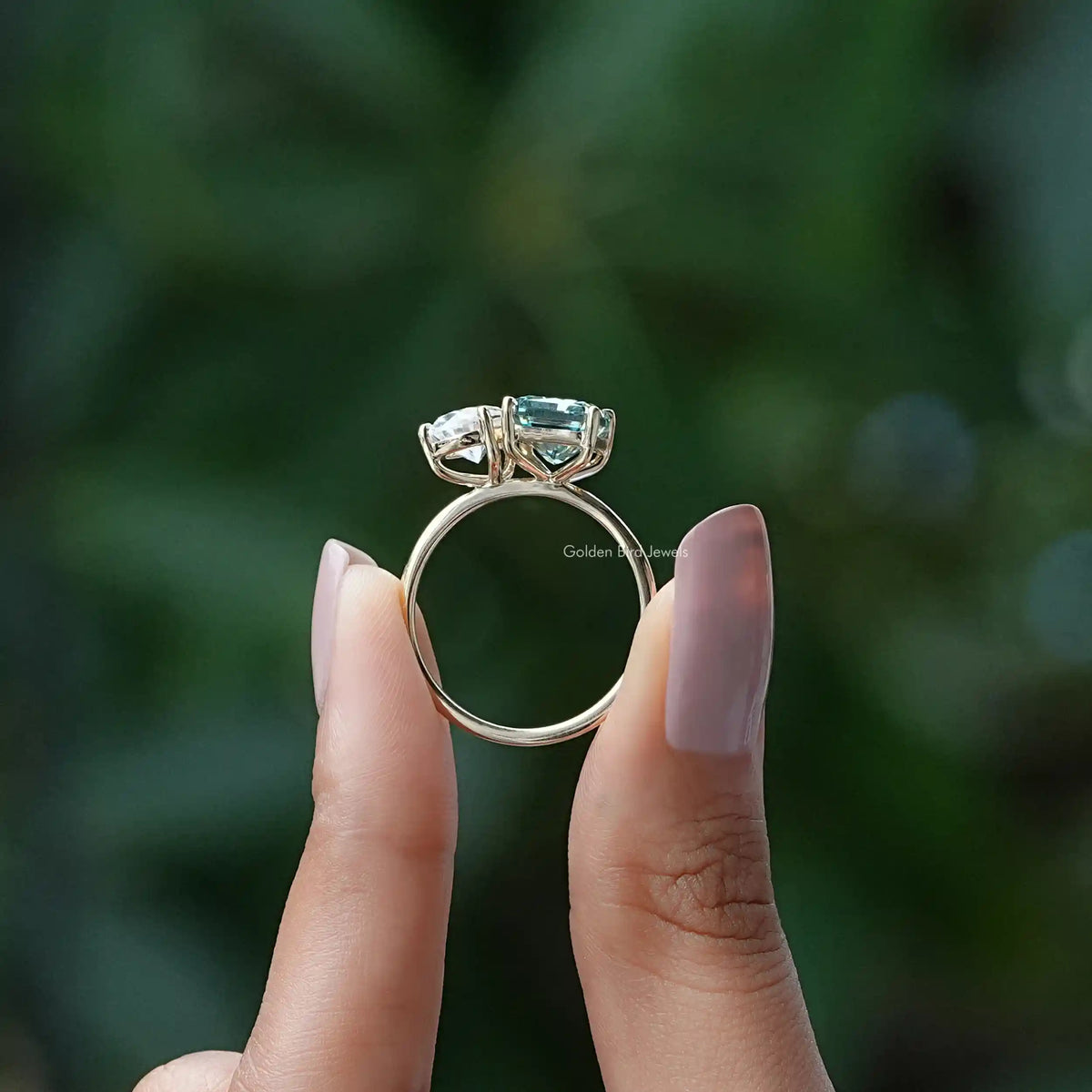 Silver ring showing prong setting with green and clear gemstones