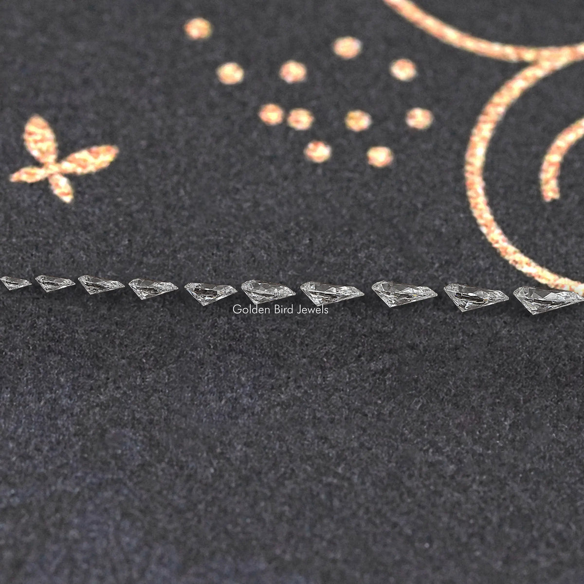 Row of small pear-shaped lab-grown diamonds on dark velvet display
