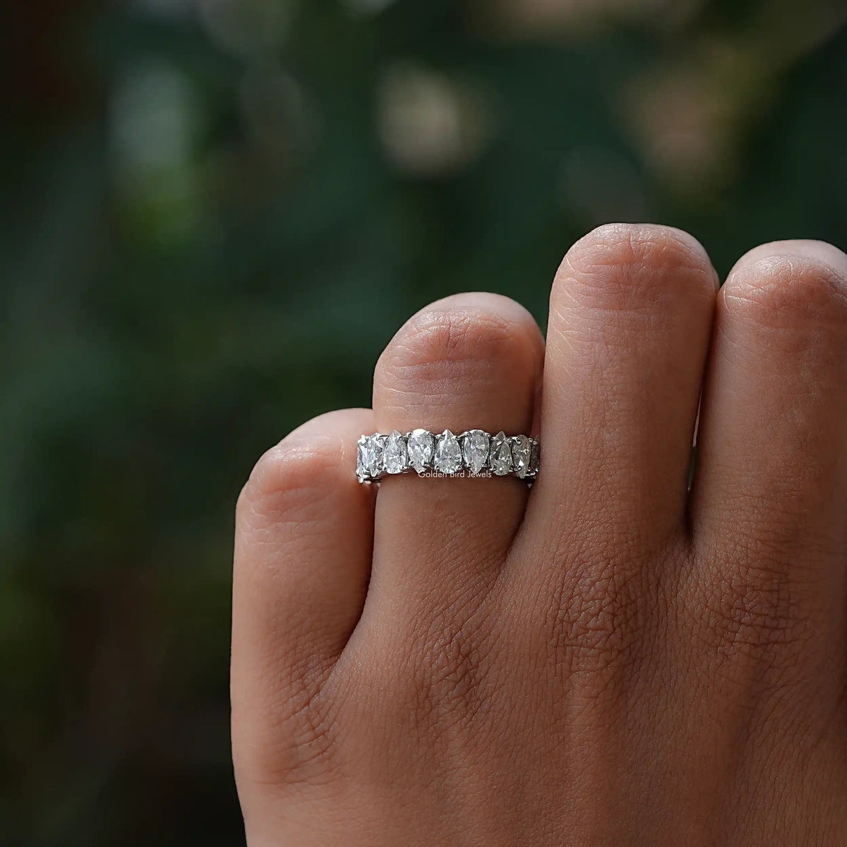 Silver moissanite eternity band with prong-set sparkling stones, top view on finger