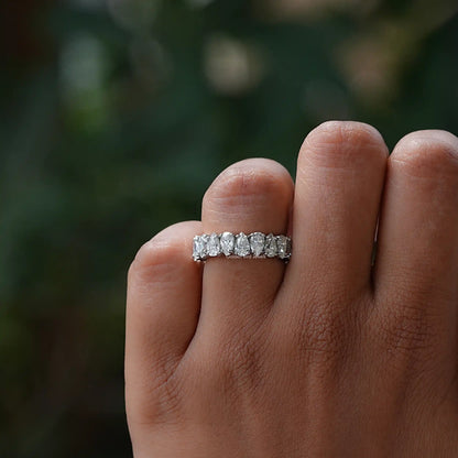 Silver moissanite eternity band with prong-set sparkling stones, top view on finger