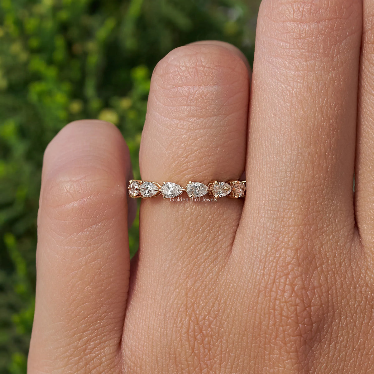 Pear-shaped eternity band ring with prong-set stones on hand