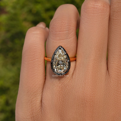 Bezel-set pear-cut gemstone engagement ring, front view on hand