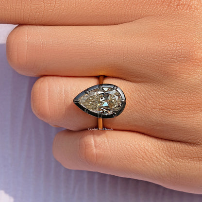 Bezel-set pear-cut gemstone ring, close-up angle showing prongs and band