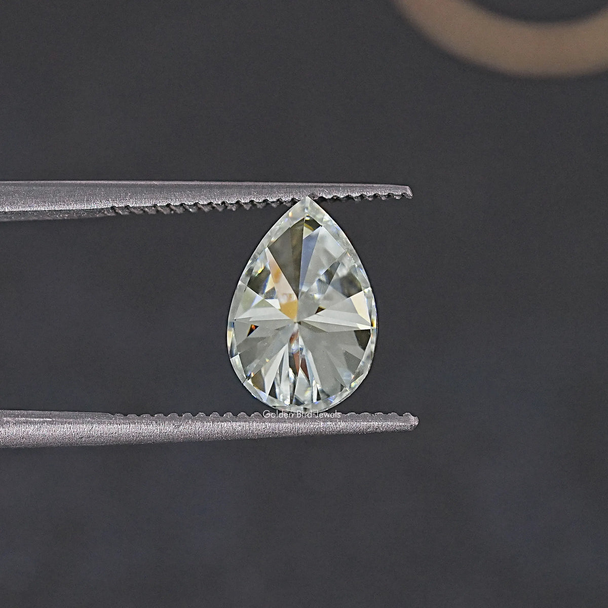Pear-cut colorless moissanite held by two metal prongs.