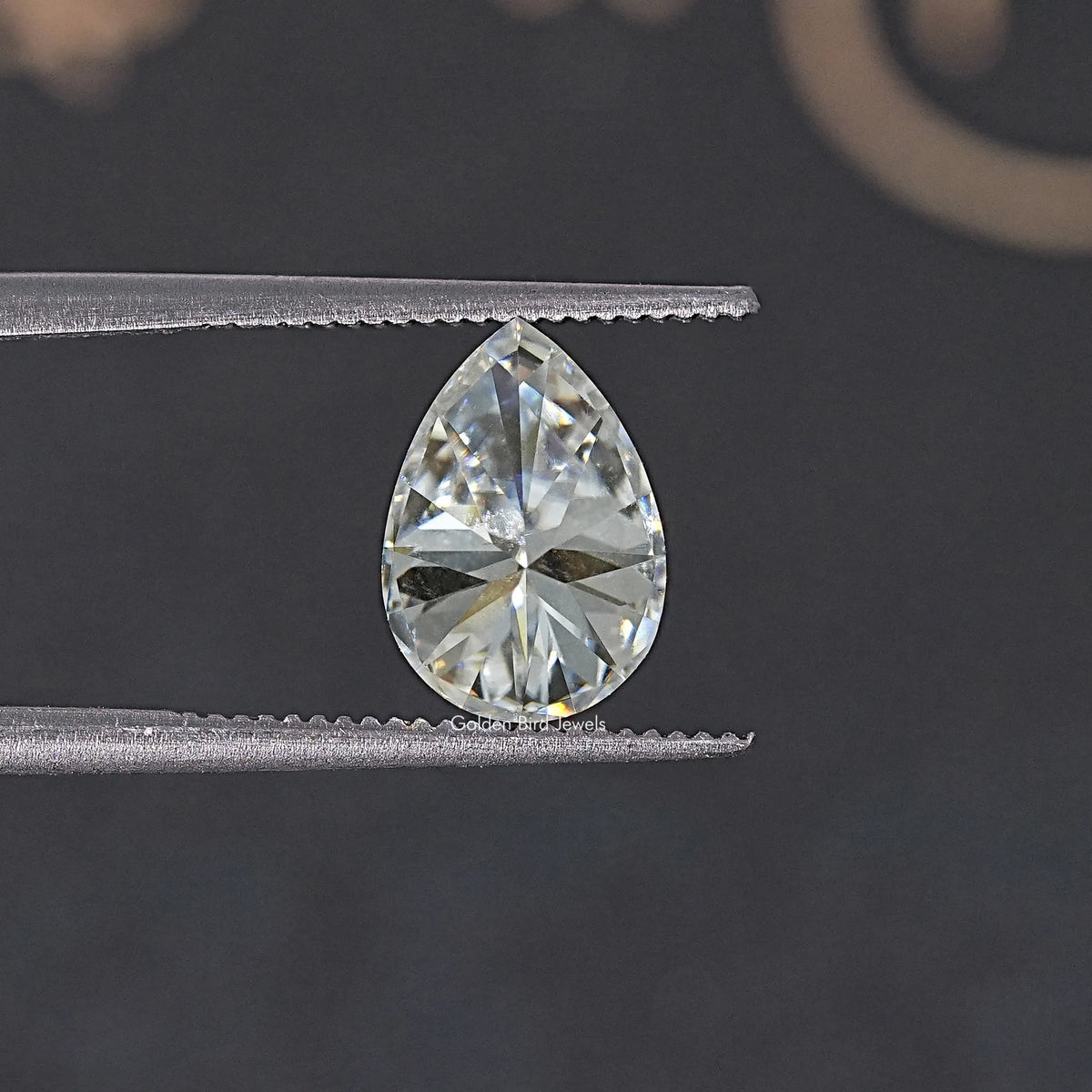 Near colorless pear-cut moissanite loose gemstone, tweezers close-up
