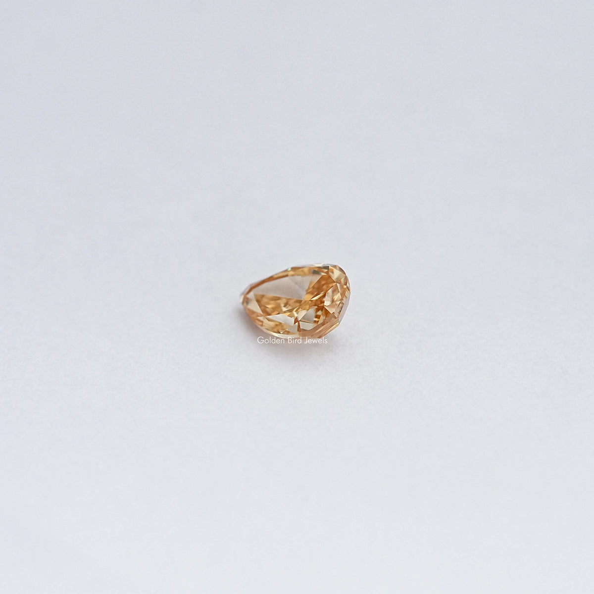 Pear-cut moissanite loose stone, warm golden color, angled top view